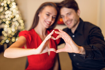 Happy smiling couple making heart shape with hands,