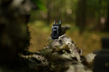 military takes aim from a pistol, forest camouflage suit, military disguise