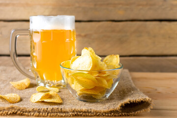 Glass of beer with potato chips on a wooden background. side view.
