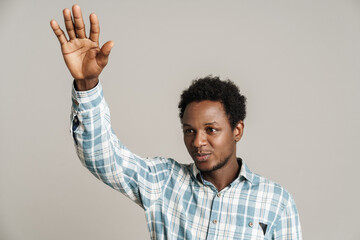 Black unshaven man waving hand while looking aside