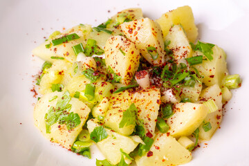 Potato salad with green onion on white plate over wooden background with copy space. Top view, flat lay food