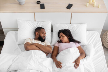 Young african american wife and husband sleeping together on comfortable bed with soft pillow, white blanket