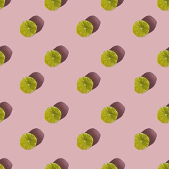 Pattern of dried lime slices with shadow on a pink background