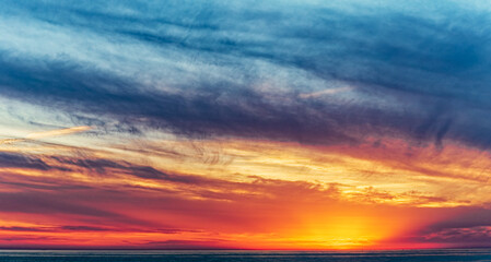 Dramatic sunset sky Background. Golden hour. Clouds and sun by the horizon. Soft focus.