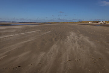 Wind blowing the sand along the beach at Camber Sands, East Sussex, England