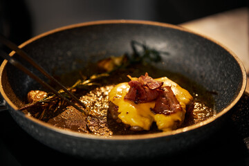 Close up view of preparation homemade beef burger on grill. Frying and smoking appetizing juicy beef in pan with rosemary, cheese and becon, isolated on black background. Concept of food.