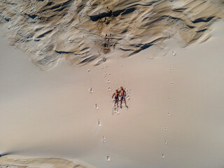 Aerial view of two kids laying on the sand