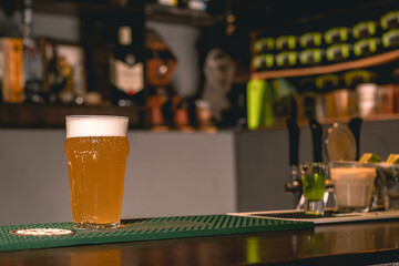 Bar counter in pub with glass of wheat beer with foamy head