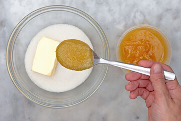 Hand putting honey in sugar and butter in bowl