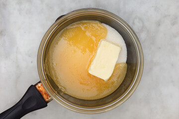 Bain-marie with sugar, butter and honey on saucepan