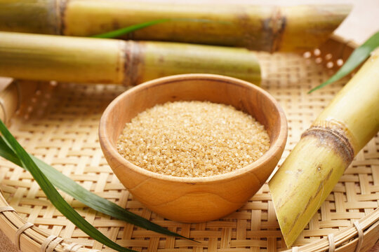Brown sugar and sugarcane in a wooden tray. Close-up. - Powered by Adobe