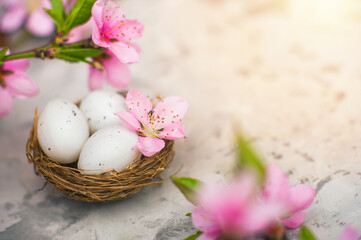 Spring blossom, Easter concept, miniature bunny, flowering tree close-up and copy space. Pink natural texture of natural flowering tree. Easter egg and branches of blossoming on an table..