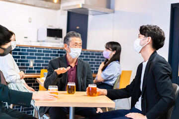 マスクをしてレストランで会話をする人々