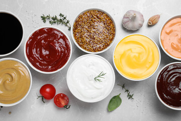 Many different sauces on light grey table, flat lay