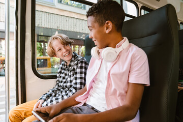 Boys laughing and using mobile phone while going on school bus