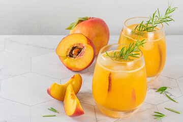 Healthy summer juice - peach cocktail with ice, rosemary twig, sugar rim, fruit slices in misted...
