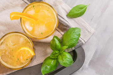 Healthy juice from oranges with basil leaves in glass, selective focus