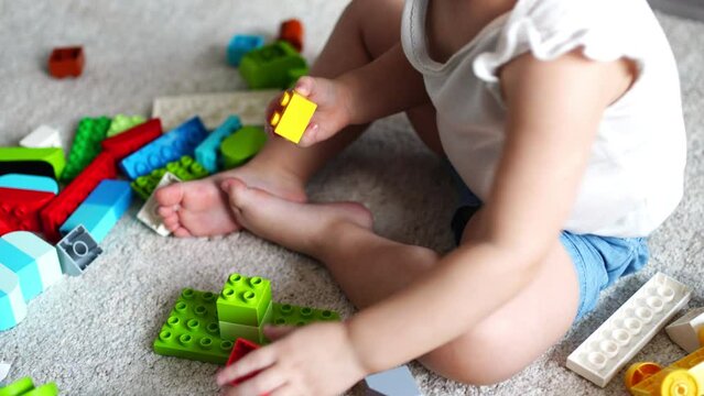 Caucasian child a little girl is playing in the constructor at home. Educational toys for children.