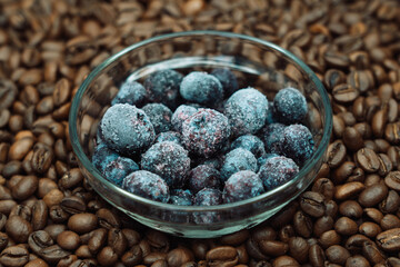 frozen blueberries in a glass transparent plate against the background of roasted coffee beans