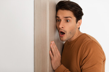 Shocked young guy listening through the door