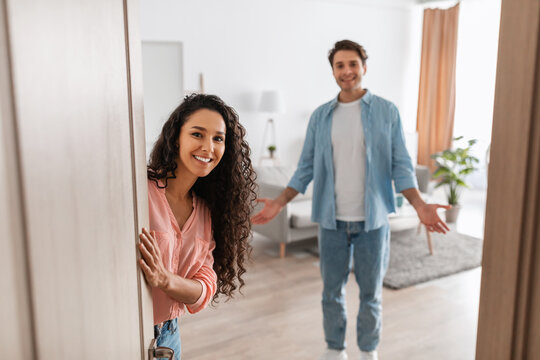 Happy young couple inviting people to enter their apartment