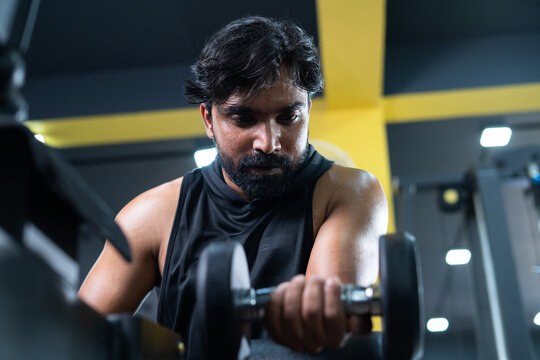 young man doing forearms workout using dumbbells at gym - cocept of fitness training, bodybuilding and healthy lifestyle.