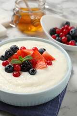 Delicious semolina pudding with berries on white marble table
