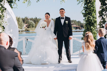 Congratulations to the newlyweds on the background of the wedding arch. Floral arch of white...