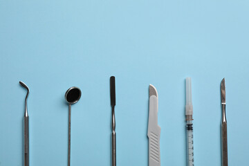 Set of different dentist's tools and syringe on light blue background, flat lay. Space for text