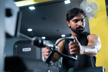 Fototapeta na wymiar young man busy exercising for chest while listening music on wireless headphone at gym - concept of body building, morning routine and fit healthy lifestyle.