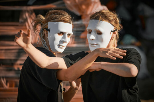 Two women in white theatre mask dancing on art festival, outdoor art theatrical performance festival