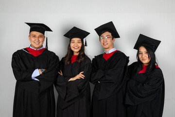 Group of graduate students friends pose together smiling in gowns and capes