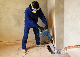 Worker with a jackhammer drilling concrete