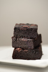 Stack of homemade chocolate brownies on a saucer, gray table and background with place for text. Vertical photo with shallow depth of fields.