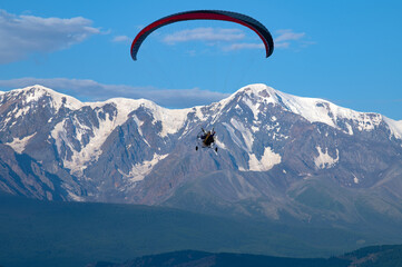 paraglider with a motor with two pilots on the background of Mount Aktru in the Altai mountains
