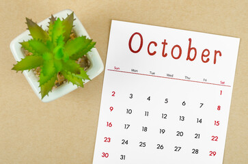 October 2022 calendar with plant pot on brown paper background.