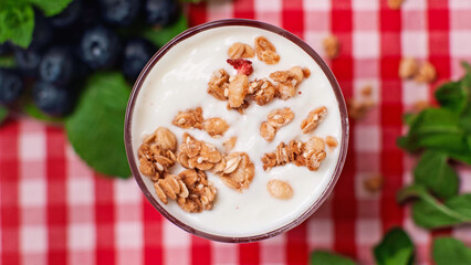 top view of crunchy granola on top of fresh yogurt in glass