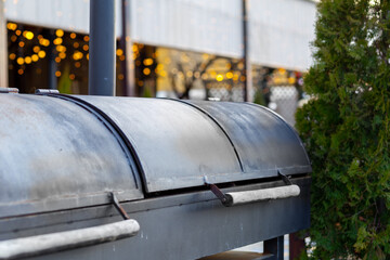 professional barbecue grill for grilling sausages outdoors in the park by the lake