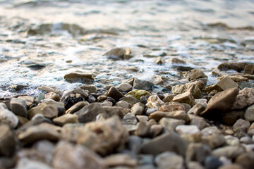 Pebbles on beach and  calm the sea, close up view. Summer holidays, vacation concept.