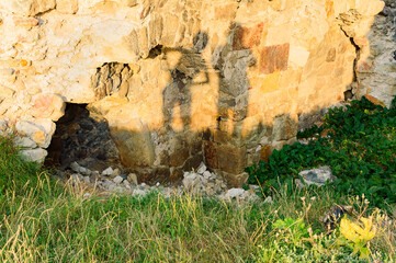 Two human shadows on the ancient Surami fortress ruined stone wall in Georgia. Green grass and evening sunlight