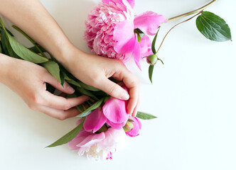Obraz na płótnie Canvas Female hands are holding pink peony flowers. Floral composition. Feminine-styled stock image. Selective focus, blurred background. Spring flowers. Spring background. A place for your text.