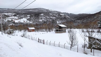 Fototapeta na wymiar View of houses in a small Bosnian village in a snowy winter.