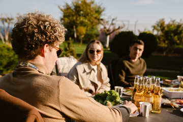 White friends smiling and talking during lunch on backyard