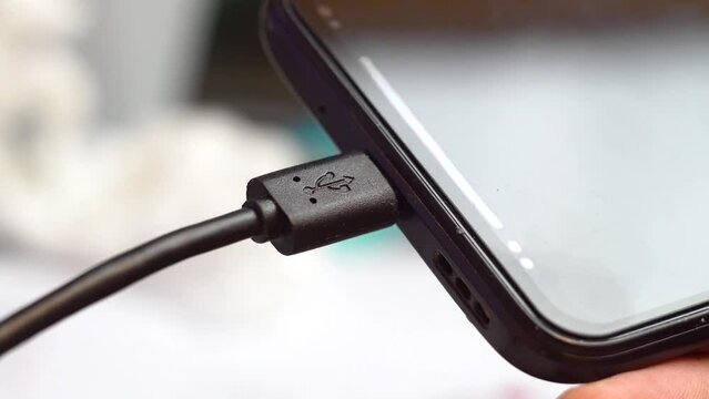 The USB plug is inserted into the smartphone. Connecting an electronic device. Data transfer. Accumulator charging. Device operation. Close-up.