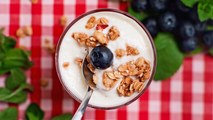 top view of blueberry and granola on top of fresh yogurt in glass with spoon