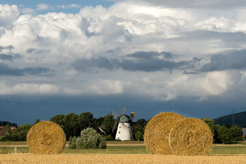 Strohballen auf dem Feld mit historischer Windmühle