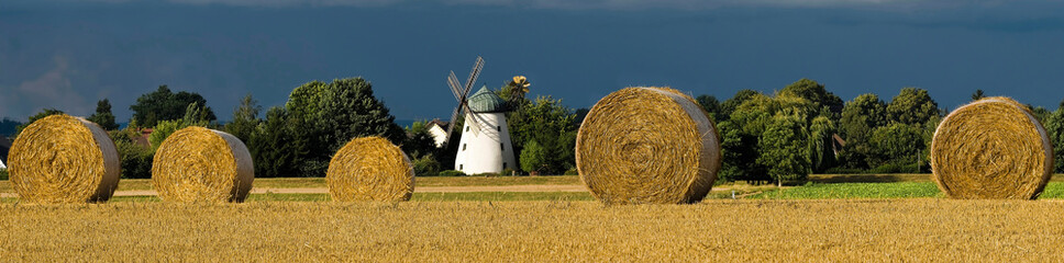 Strohballen auf dem Feld mit historischer Windmühle
