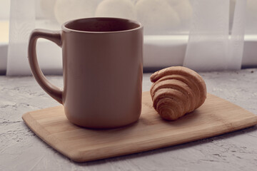 coffee mug and croissant on cutting board