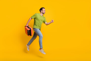 Fototapeta na wymiar Full body profile side photo of young man runner jumper rush hold bag journey weekend abroad isolated over yellow color background