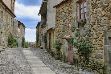 Narrow street with flowers and old stone houses, Castelo Rodrigo village, Serra da Estrela, Beira...